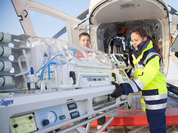 Draeger transport incubator being loaded into helicopter by 2 medical staff